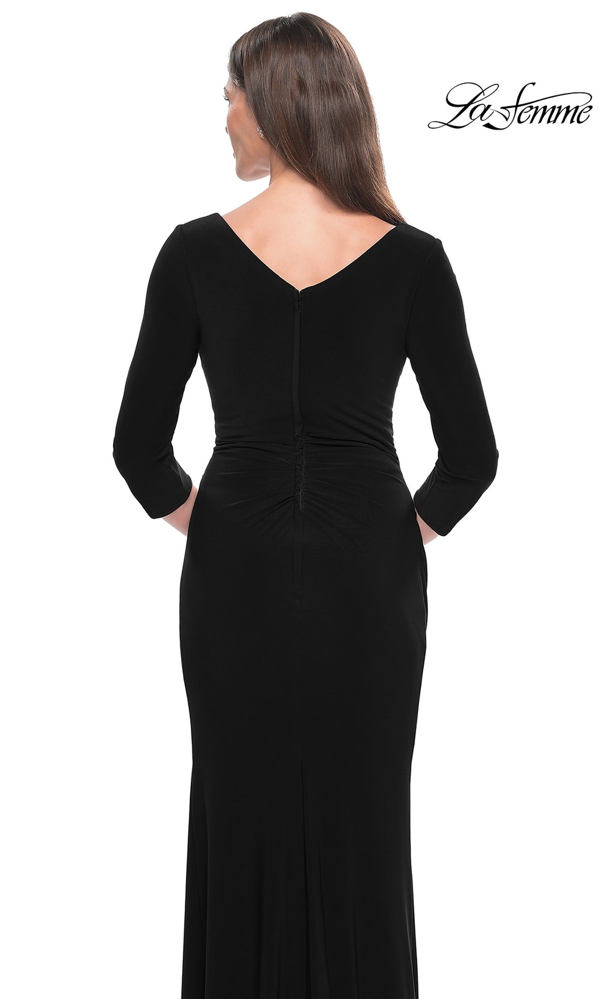 A woman is shown from the back wearing the La Femme Long-Sleeve Fitted Formal Dress 31020, a black floor-length jersey dress with a V-shaped back, subtle waist ruching, and her straight brown hair down.